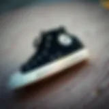 Classic black Converse Chuck Taylor shoes on a textured surface